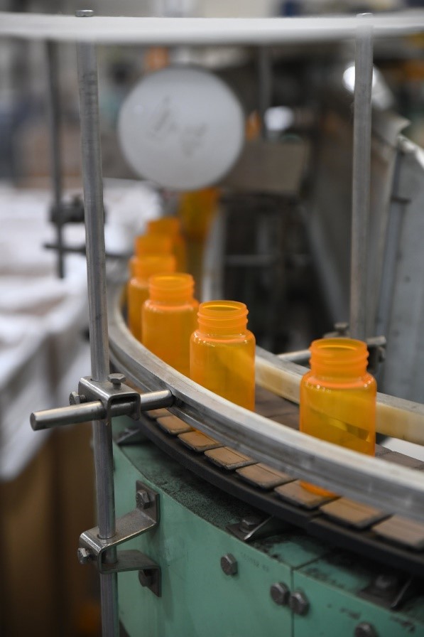 Orange pill bottles on an assembly line conveyor belt