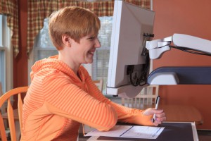 Young woman with visual impairment working at her desktop magnifier