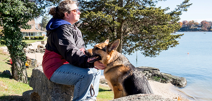 Dixie Sanderson on the shore of Long Island Sound with her guide dog, Jayla.