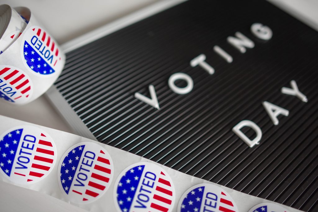 Sign which says "Voting Day" and a roll of stickers which read "I voted" in the style of the American Flag