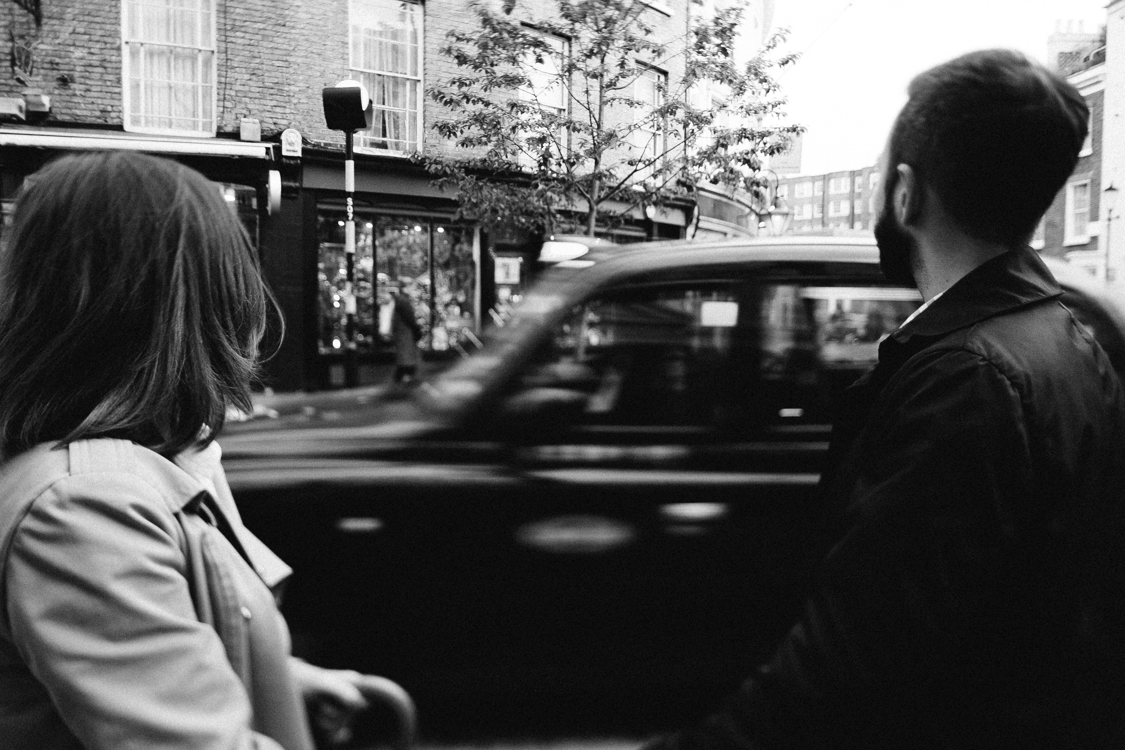 Taxi passes by man and woman on the street.