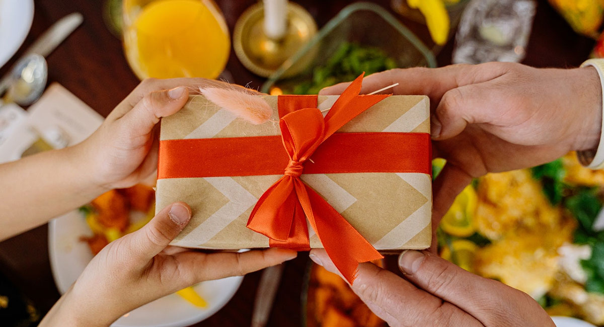 A photo of a pair of hands giving a gift and another pair of hands accepting that gift.