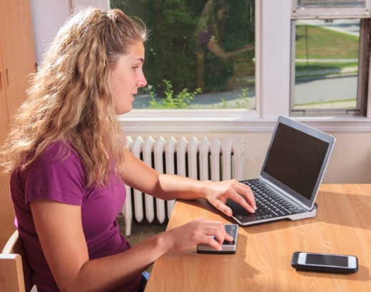 Woman using a laptop with a screen reader and a braille display